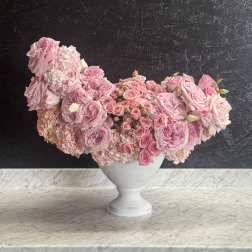 Pink rose arrangement in a white pedestal vase