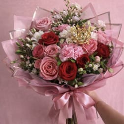 Pink and red rose bouquet wrapped in pink paper with a satin ribbon