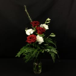 Red and white roses in a clear glass vase with greenery