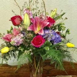 Mixed bouquet with pink lilies, roses, and purple hydrangeas in a glass vase