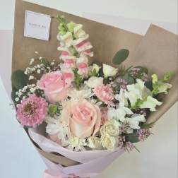 Hand-tied bouquet of pink and white flowers wrapped in brown paper