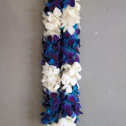 A long floral lei made of white and blue-purple blossoms.
