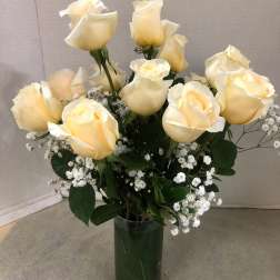 Cream roses arranged in a clear glass vase with small white filler flowers
