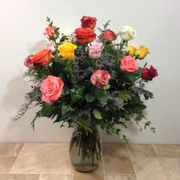 Mixed roses in a glass vase with purple filler flowers
