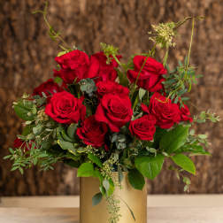 Arrangement of red roses in a gold cylinder vase on a marble surface