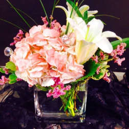 Pink hydrangeas and white lilies in a clear glass vase