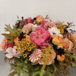 Mixed bouquet of pink, peach, and yellow flowers in a glass vase