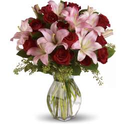 Red roses and pink lilies arranged in a clear glass vase