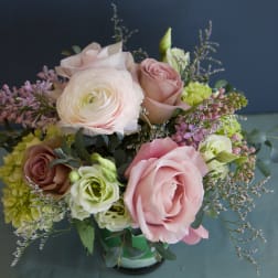Bouquet of pink and white roses with purple filler flowers in a glass vase