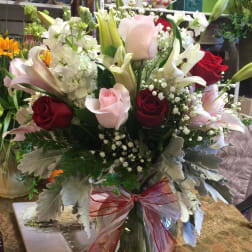 Bouquet of red and pink roses with white lilies in a glass vase