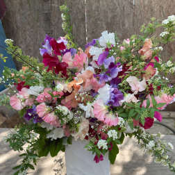 Large bouquet of pink, purple, white, and peach sweet peas in a white vase