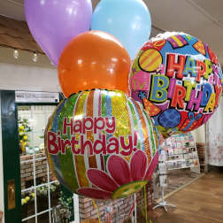 Birthday balloons in pastel colors and two printed Happy Birthday balloons