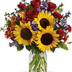 Bouquet of sunflowers, red roses, and purple flowers in a glass vase