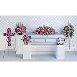 Pink and purple funeral floral arrangements around a silver casket