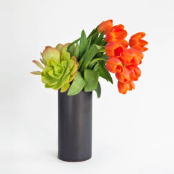 Orange tulips and a green succulent in a black vase