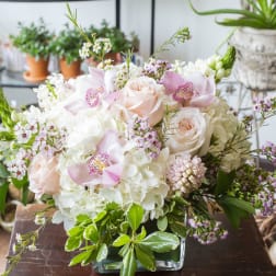 Pink roses and white hydrangeas in a glass vase with small accent flowers