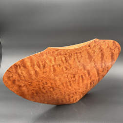 Curved wooden bowl with a glossy burl finish on a dark background