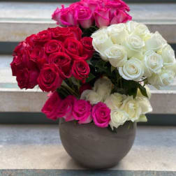Three rose bouquets in pink, red, and white arranged in a round vase
