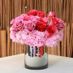 Pink and red roses arranged in a mirrored vase