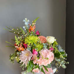 Mixed bouquet with pink, white, and green flowers in a pink container
