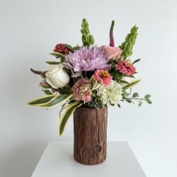 Mixed bouquet in a rustic wooden vase with pink, white, and lavender flowers