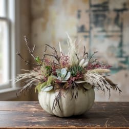 Pumpkin-shaped container with a dried floral arrangement in muted tones