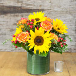 Sunflowers and orange roses in a green glass vase