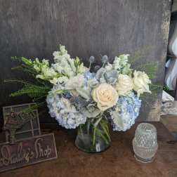 White and pale blue flower arrangement in a glass vase