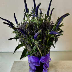 Purple flower arrangement in a glass vase with a ribbon bow