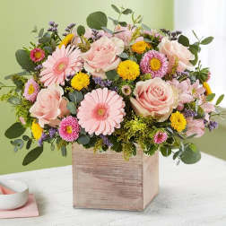 Pink roses and daisies arranged in a wooden box