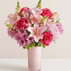 Pink and lavender bouquet with roses and lilies in a tall pink vase
