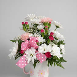 Pink and white flower arrangement in a white mug with a polka-dot bow