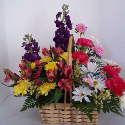 Basket arrangement with mixed flowers in purple, pink, yellow, and white