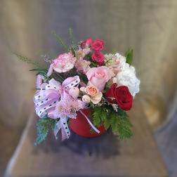 Mixed bouquet in a red hatbox with pink, red, and white flowers