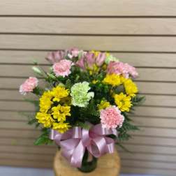 Bouquet of yellow and pink flowers tied with a pink ribbon in a vase