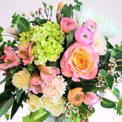 Mixed bouquet of pink, white, and green flowers in a glass vase