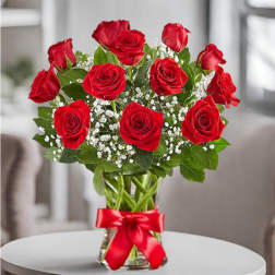 Bouquet of red roses in a clear glass vase with a red ribbon