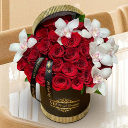Red roses and white orchids arranged in a black hatbox