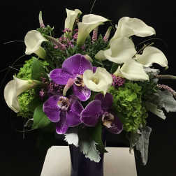Purple orchids and white calla lilies in a dark vase
