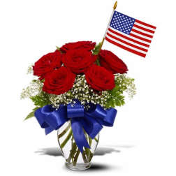 Red roses in a glass vase with a blue ribbon and small American flag