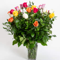 Mixed roses in a clear glass vase with dense greenery