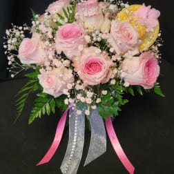 Pink roses with baby's breath and ribbon accents in a bouquet
