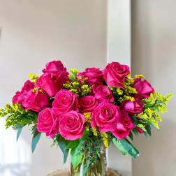 Pink rose bouquet in a clear glass vase with yellow filler flowers