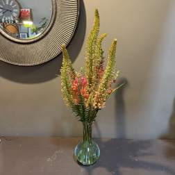 Tall mixed flower arrangement in a glass vase with pink and yellow blooms