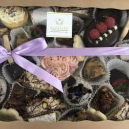 Assorted chocolates in a gift box tied with a lavender ribbon.