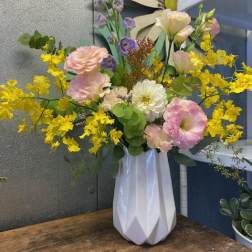 Pastel floral arrangement in a white vase with yellow and pink blooms