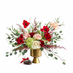 Red and blush roses in a gold vase with a small wrapped chocolate gift
