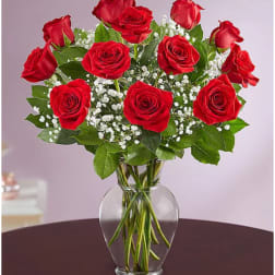 Red roses arranged in a clear glass vase with white baby's breath