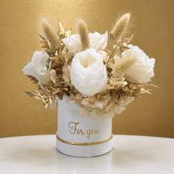 White floral arrangement in a white container with gold accents