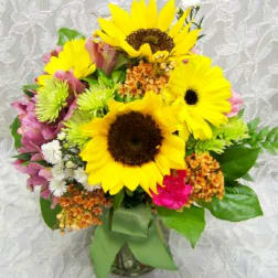 Bouquet of yellow sunflowers and mixed pink flowers in a glass vase